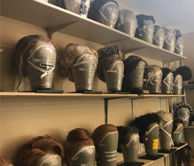 Various wigs from My Fair Lady on wig stands backstage.